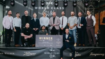 Skupina približne 13 mužov v oblekoch stojí na pódiu s podsvietením a bannermi festivalu World Class Slovakia, jeden z nich drží víťaznú cenovú tabulu.